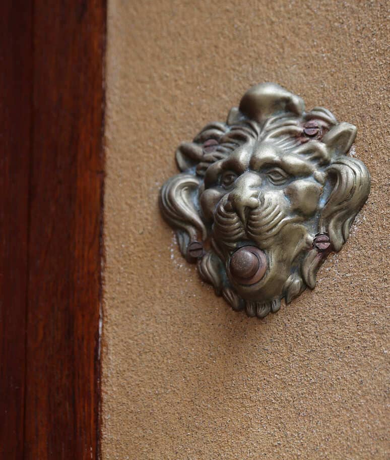 Batacchio in bronzo a forma di testa di leone su portone storico di Chianalea